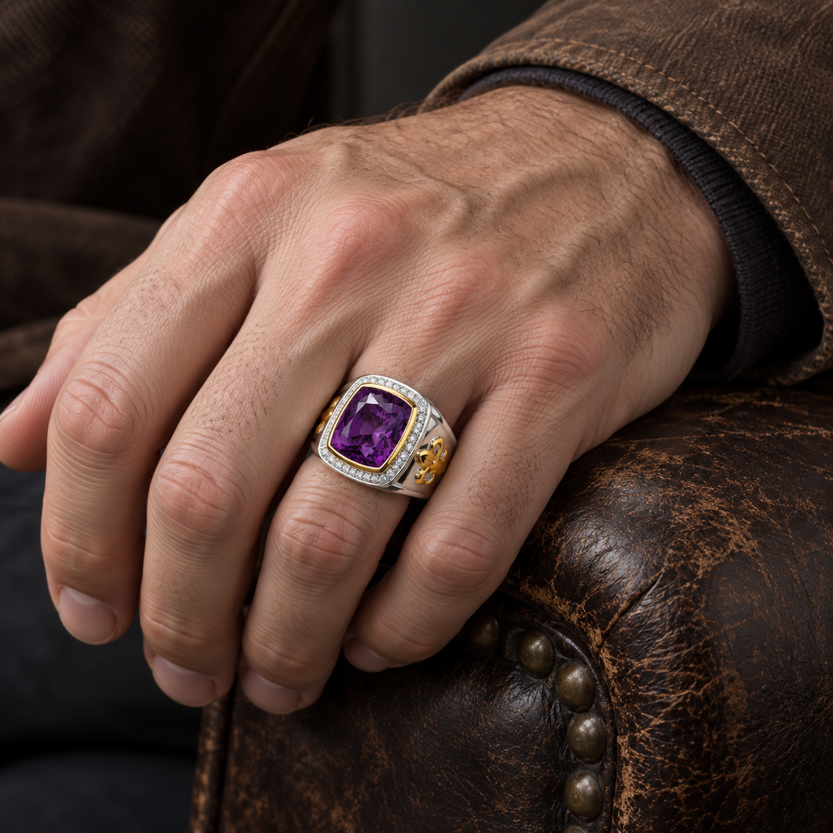 แหวนอเมทิสต์เงินแท้ 925 เฟลอร์เดอลิสชุบทอง 14K สวมบนมือที่วางบนเก้าอี้หนัง